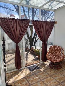 a conservatory with curtains and a chair on a patio at Casa María Sabina in San Juan del Río