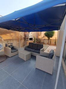 a blue umbrella on a patio with couches and chairs at Villa rotana airport road in Al Qasţal