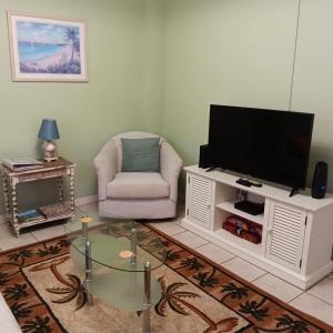 a living room with a tv and a chair at Cozy Beach Getaway in Cape Canaveral