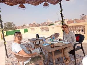 zwei Personen sitzen an einem Tisch auf einer Terrasse in der Unterkunft four pyramids Guest house in Kairo