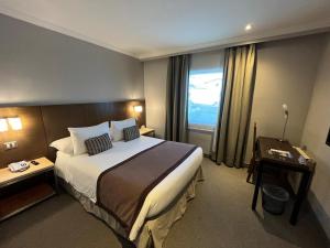 a hotel room with a large bed and a window at Hotel Martín Gusinde in Puerto Natales