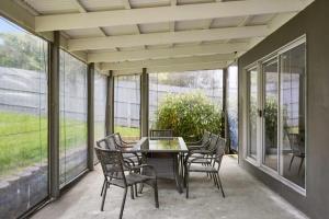 a table and chairs on a patio with windows at Modern Beach House - Dromana in Mornington