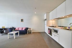 a kitchen and living room with a couch and a table at Docklands Convenient & Modern 1 Bed Apartment in Melbourne