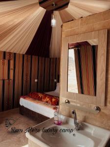 a bathroom with a sink and a mirror and a bed at Rum Mere luxury camp in Wadi Rum
