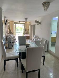 ein Esszimmer mit einem Glastisch und weißen Stühlen in der Unterkunft Apartamento Amoblado en Rodadero de Santa Marta in Rodadero