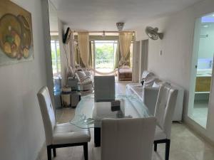 ein Esszimmer mit einem Glastisch und weißen Stühlen in der Unterkunft Apartamento Amoblado en Rodadero de Santa Marta in Rodadero + 14 Fotos