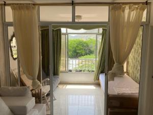 ein Schlafzimmer mit einem Bett und einem Fenster mit Vorhängen in der Unterkunft Apartamento Amoblado en Rodadero de Santa Marta in Rodadero