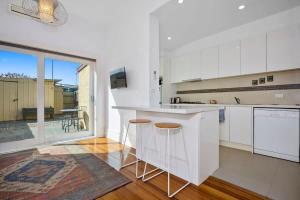 a kitchen with white cabinets and a large window at Yarraville - Modern Historic Home in Yarraville