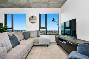 sala de estar con sofá y algunas ventanas en Stylish City Apartment - City View Pool & Gym, en Melbourne