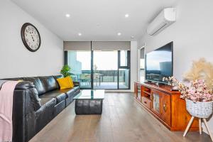 sala de estar con sofá de cuero negro y reloj en Sunview Modern 2-Bed with City Views, en Sunshine