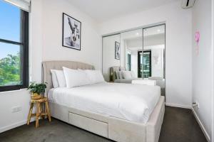 a bedroom with a large white bed and a mirror at 2BR Penthouse Apt Rooftop Terrace, Spa & BBQ in Melbourne