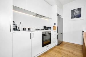a white kitchen with white cabinets and appliances at 2BR Penthouse Apt Rooftop Terrace, Spa & BBQ in Melbourne