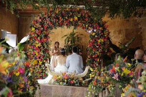 Una novia y un novio sentados bajo un arco de flores en Hotel Hicasua y Centro de Convenciones, en Barichara
