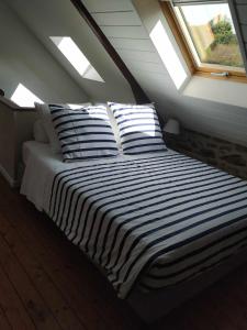 un letto con cuscini a righe in mansarda di studio Marie a Cancale