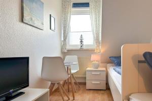 Habitación pequeña con cama y escritorio con TV. en Ferienwohnung-4-mit-Sonnenbalkon-im-Landhaus-Hubertus-Duhnen, en Cuxhaven