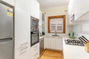 a kitchen with white appliances and a window at Beachside Living in Modern 2 bedroom Apartment in Sydney