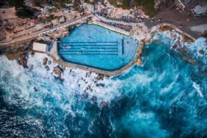 an aerial view of a swimming pool next to the ocean at Beachside Living in Modern 2 bedroom Apartment in Sydney