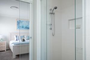 een badkamer met een inloopdouche naast een bed bij Spacious And Luxurious Beach Home in Catherine Hill Bay
