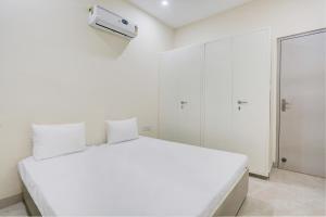 OYO Gaur Nitay في Dahmi: غرفة نوم بيضاء مع سرير أبيض ونافذة