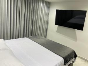 een slaapkamer met een bed en een flatscreen-tv bij Hermoso apartamento en El Poblado in Medellín