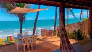 una mesa y sillas en una playa con el océano en Casa da Peroba Sol, en Icapuí
