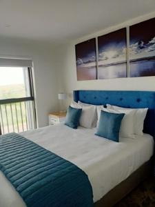 a bedroom with a large bed with a blue headboard at Beachfront Haven in Christchurch