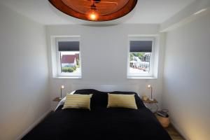 een slaapkamer met een bed met 2 ramen en een klok bij Meeresblick "Enna Mare" Haus 1 - Ferienwohnung 5 in Hohwacht