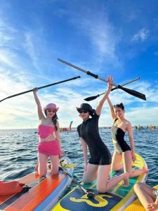 three women on a paddle board in the water at White's house in Quan Lạn