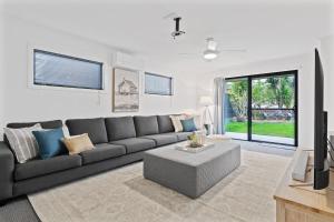 uma sala de estar com um sofá cinzento e uma mesa em Waterfront Luxury Living & Private Pool Buff Point em Budgewoi