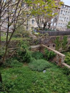 a brick wall with trees and bushes in front of a building at Chambres spacieuses hyper centre in Saint-Étienne