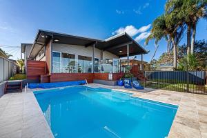 a swimming pool in front of a house at Waterfront Luxury Living & Private Pool Buff Point in Budgewoi