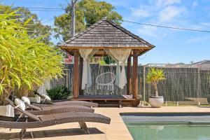a gazebo with chairs next to a swimming pool at Lake Side Luxury with a Pool, Pet Friendly in Toukley