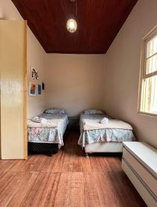 two beds in a room with a wooden floor at Casinha Verde in Passa Quatro