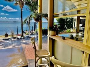 a balcony with a table and chairs and a view of the water at Absolute Waterfront Hidden Gem, Toukley in Toukley