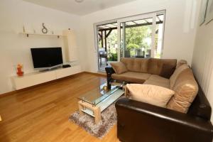 - un salon avec un canapé en cuir et une télévision dans l'établissement Apartments with a swimming pool Stobrec, Split - 22897, à Podstrana