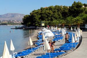 - une plage avec des chaises et des parasols bleus et blancs dans l'établissement Apartments with a swimming pool Stobrec, Split - 22897, à Podstrana