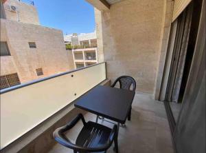 Abdoun apartment في عمّان: شرفة على طاولة وكراسي في مبنى