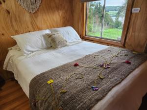 ein Bett mit Blumen darauf in einem Zimmer mit Fenster in der Unterkunft Cabañas&tinajas en Molulco-Pureo-Natri,Compu in Compu