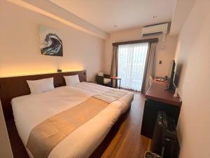 um quarto de hotel com uma cama e uma televisão em THE GRAND HOTEL GINOWAN em Ginowan
