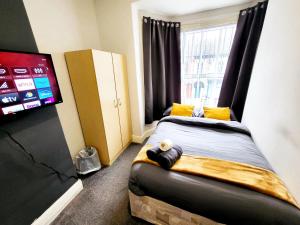 a bedroom with a bed with a flat screen tv at Stay Sleep Rest - De Grey in Hull