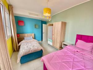a bedroom with two beds with pink and blue walls at Oran Harouni bouziane in Oran