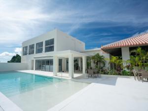 a white house with a swimming pool in front of it at Private condo Kourijima by Coldio Smart Resort in Nakijin