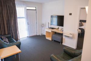 a living room with a couch and a desk with a television at Victoria Court Motor Lodge - Free Parking in Wellington