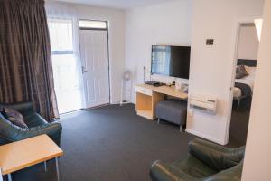 a living room with a couch and a desk with a television at Victoria Court Motor Lodge in Wellington