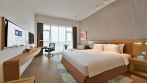 Holiday Inn Express Chengdu Huanhuaxi, an IHG Hotel في تشنغدو: غرفة الفندق بسرير كبير ومكتب