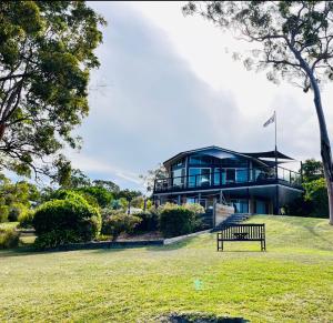 a house on a hill with a bench in front of it at SilverWaters Waterfront Accommodation in Morisset East