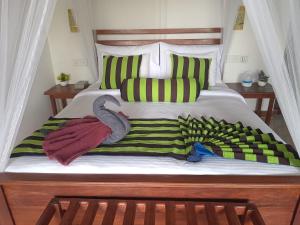 a bed with green and yellow pillows and towels at NETHSARA cottage in Ella