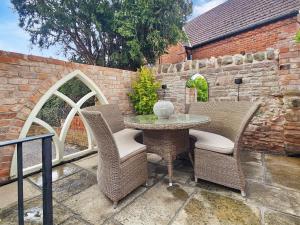 a patio with a table and chairs and a brick wall at The School Room in Dymock