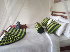 a bedroom with a bed with green and white pillows at NETHSARA cottage in Ella