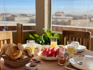 a table with a plate of food and glasses of orange juice at Hotel de Sal Atipax in Uyuni